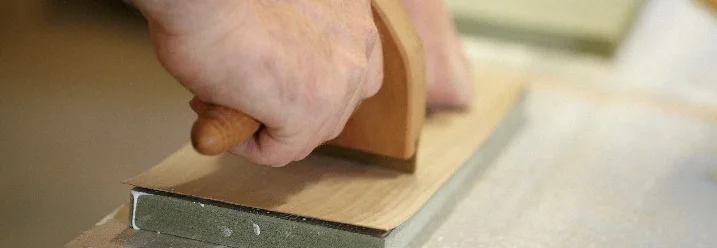 Person glättet Holz mit Hobel